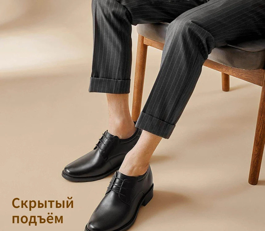 Чёрные кожаные туфли на модели в костюме, сидящей на стуле — скрытый подъём